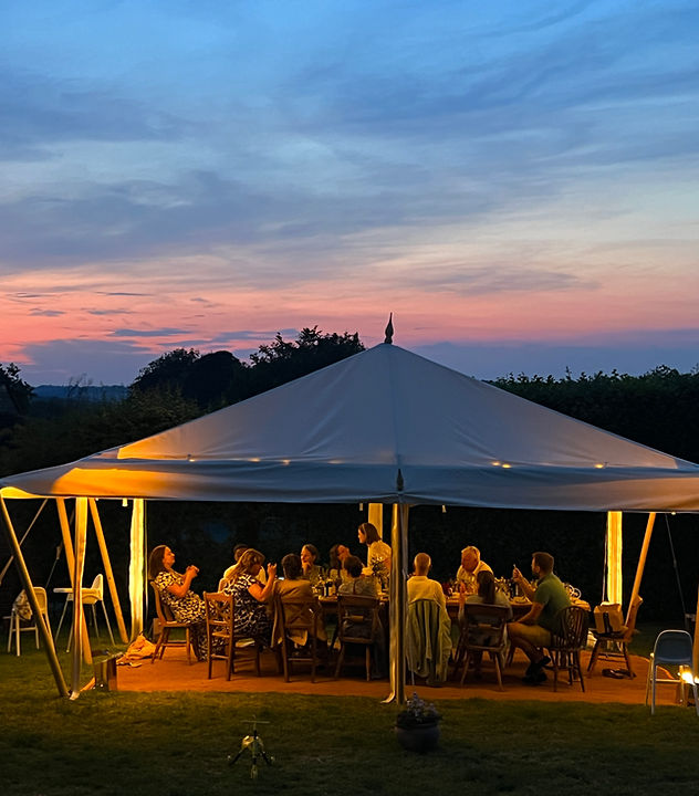 Guests dining beneath a marquee at sunset